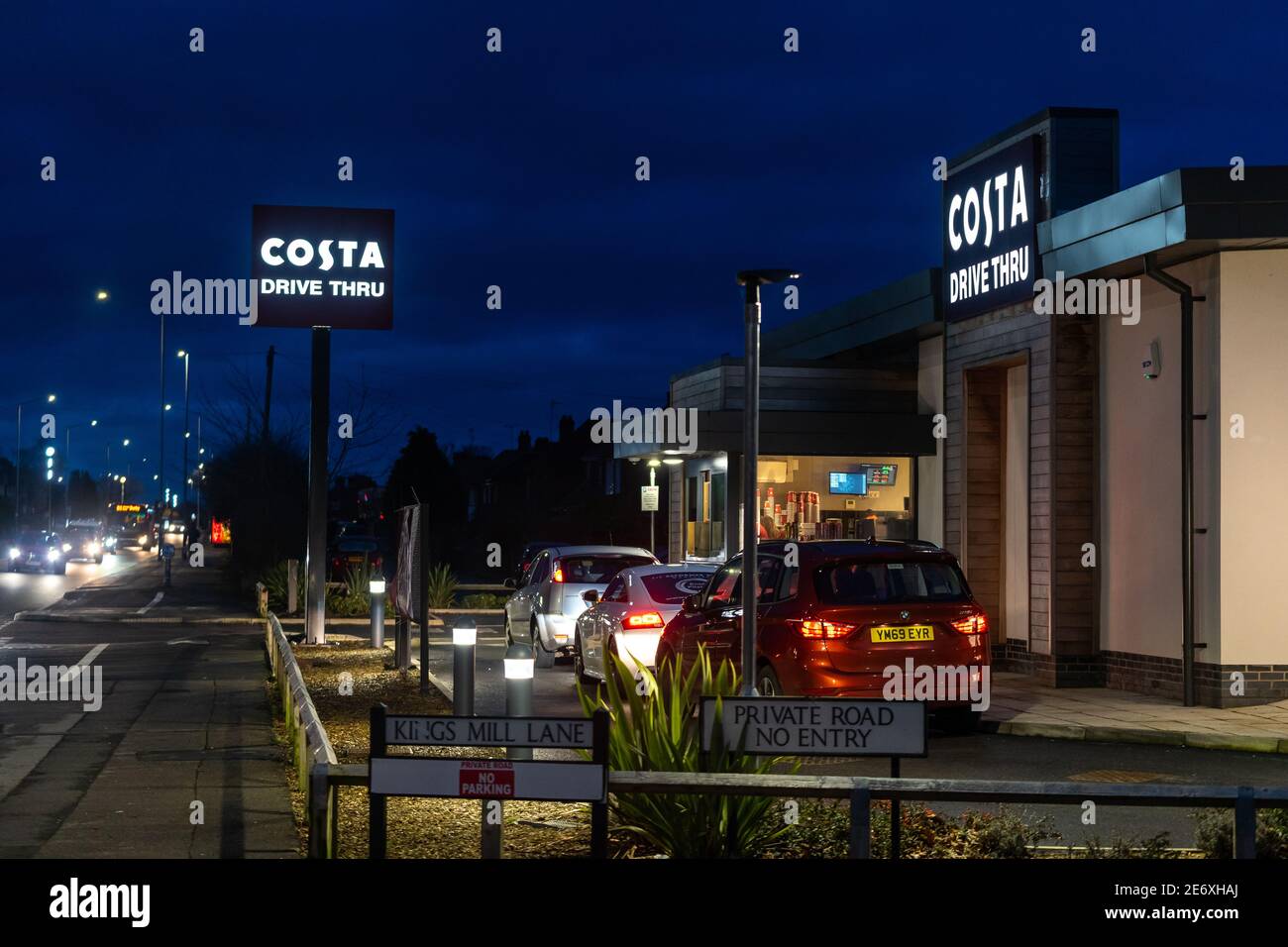 Vue nocturne du salon de café Mansfield Costa avec des panneaux allumés, les voitures font la queue et les fenêtres d'attente sont éclairées et magasin ouvert tard Banque D'Images