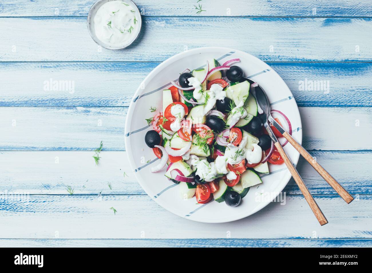 Salade grecque avec concombre, tomates, olives noires et tzatziki sur fond de bois bleu et blanc. Ambiance et inspiration marine. Banque D'Images