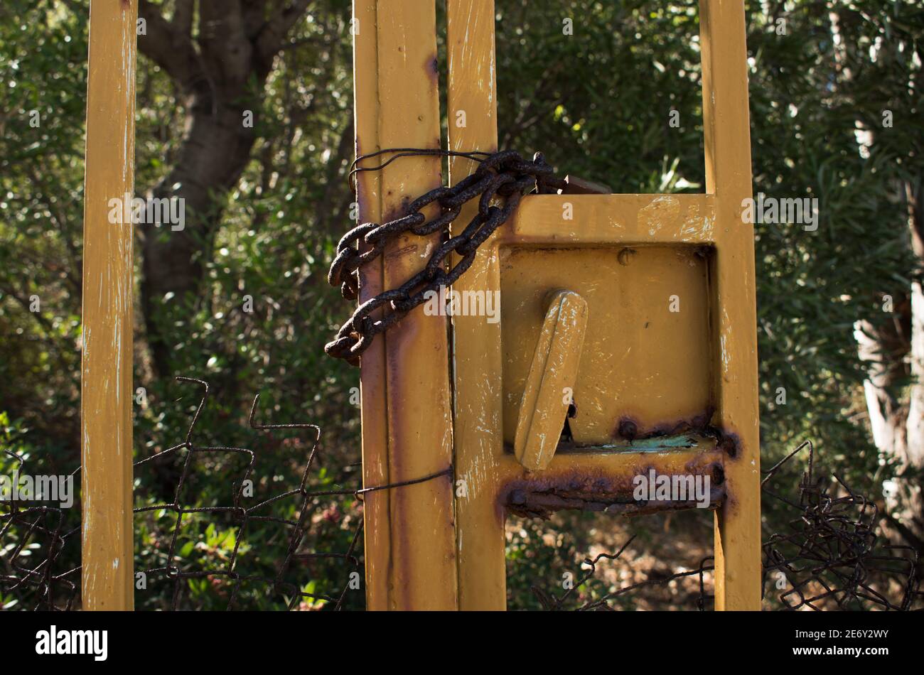 Vieille chaîne en fer rouillée à une clôture tenant un jaune porte fermée Banque D'Images