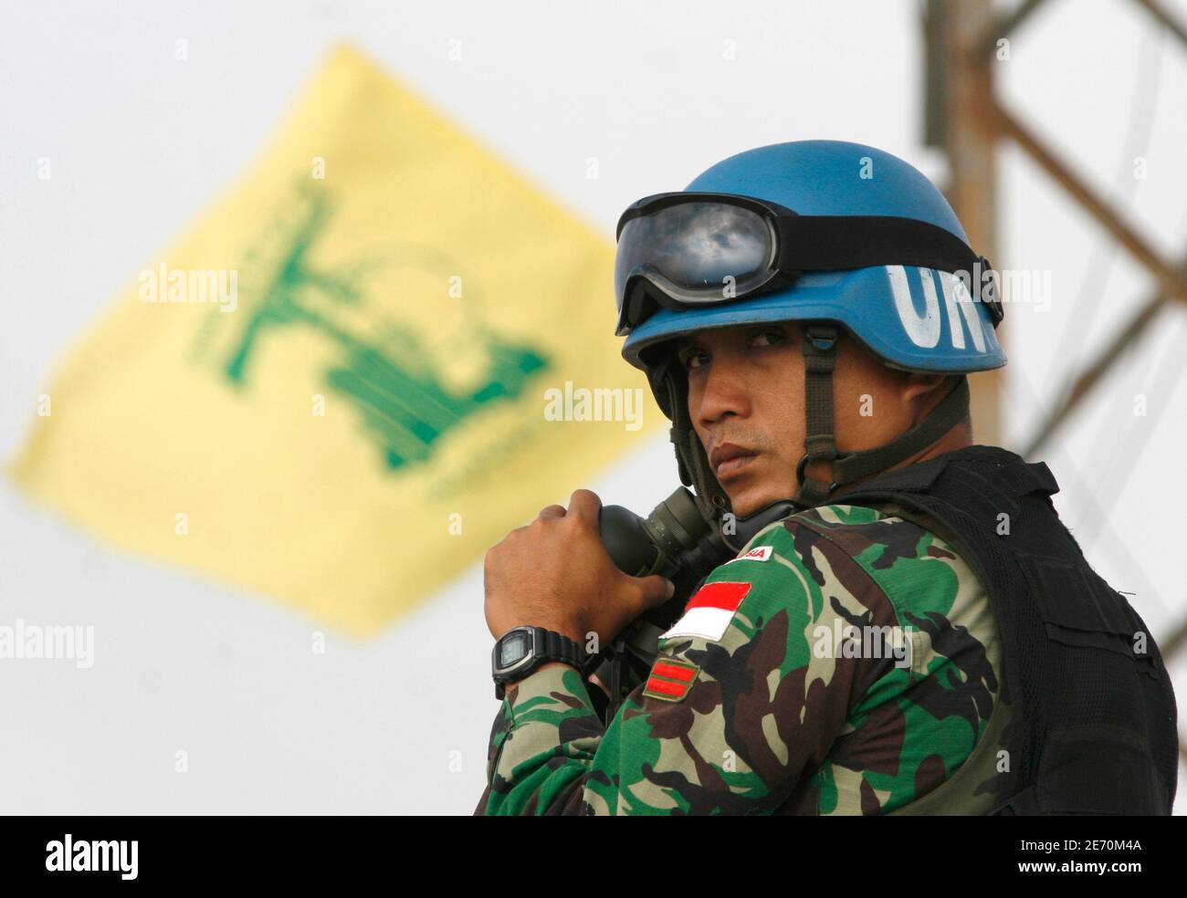 A . peacekeeper from Indonesia uses a pair of binoculars, near a  Hezbollah flag, to monitor the border with Israel in Adayssy village,  southern Lebanon June 18, 2007. Two Katyusha rockets hit