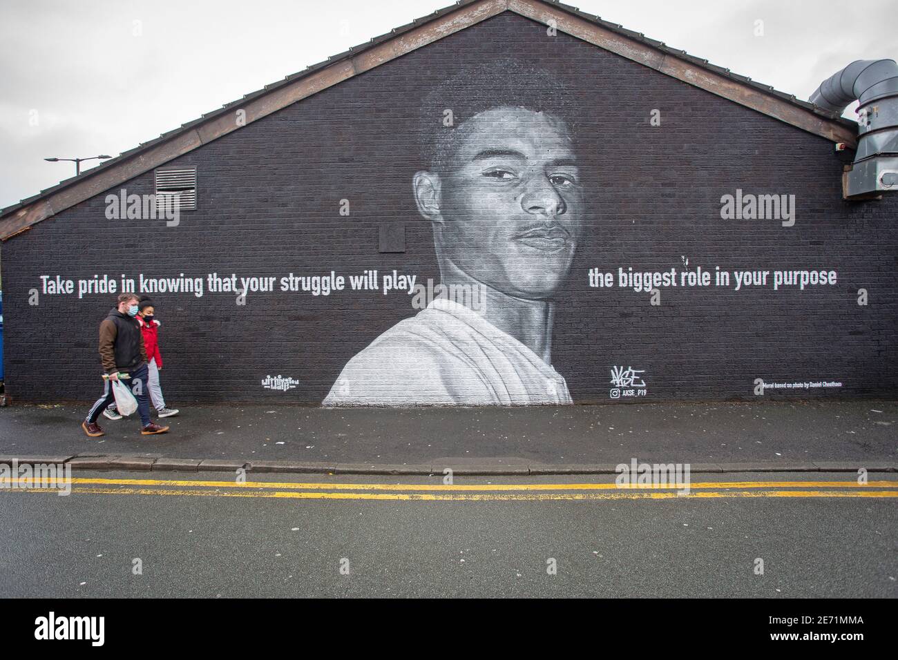 Piétons passant devant la fresque du joueur de football de Manchester United Marcus Rashford sur le côté d'un bâtiment à Withington, Manchester. Banque D'Images