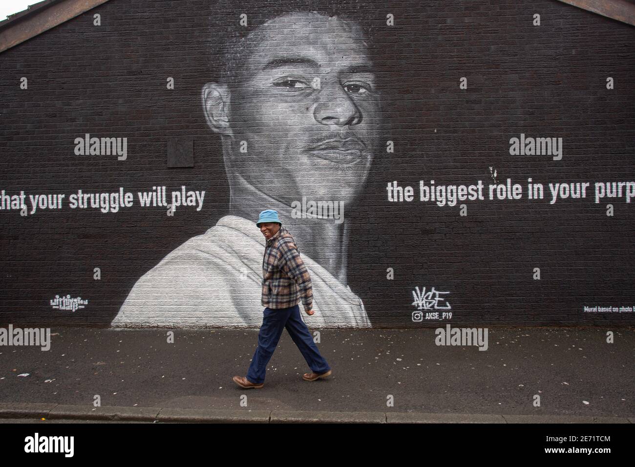 Black man passe devant la fresque du joueur de football de Manchester United Marcus Rashford sur le côté d'un bâtiment à Withington, Manchester, dans le nord-ouest de l'Eng Banque D'Images