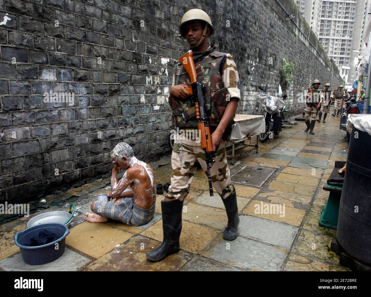 Paramilitary troops patrol a residential area as a boy takes a bath next to  Arthur Road jail in Mumbai April 16, 2009. The court-appointed lawyer for  Mohammad Ajmal Kasab, accused of being