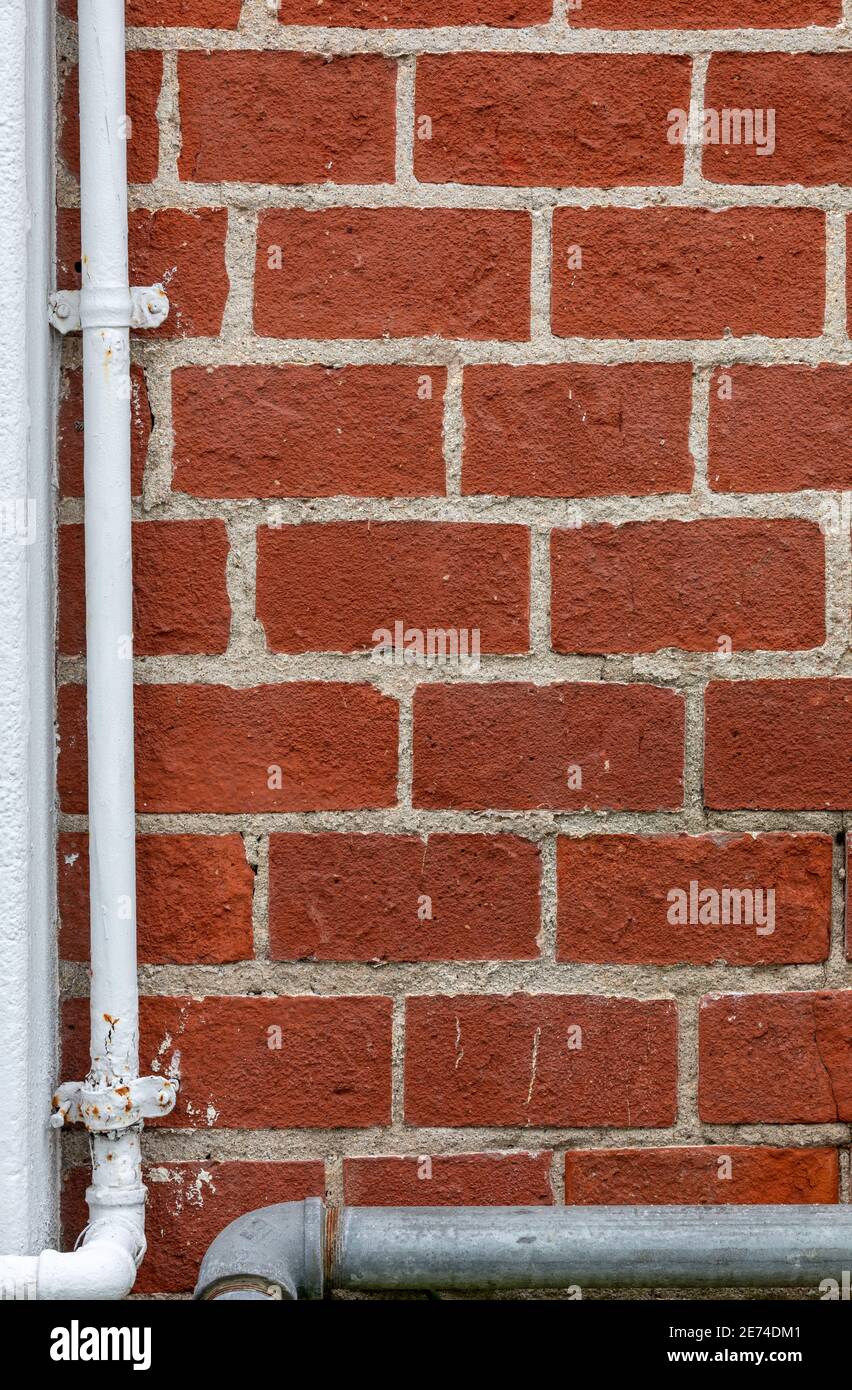 Un mur en brique rouge avec des tuyaux en acier blanc et gris à gauche et en bas, une image utile pour l'espace de copie. Banque D'Images