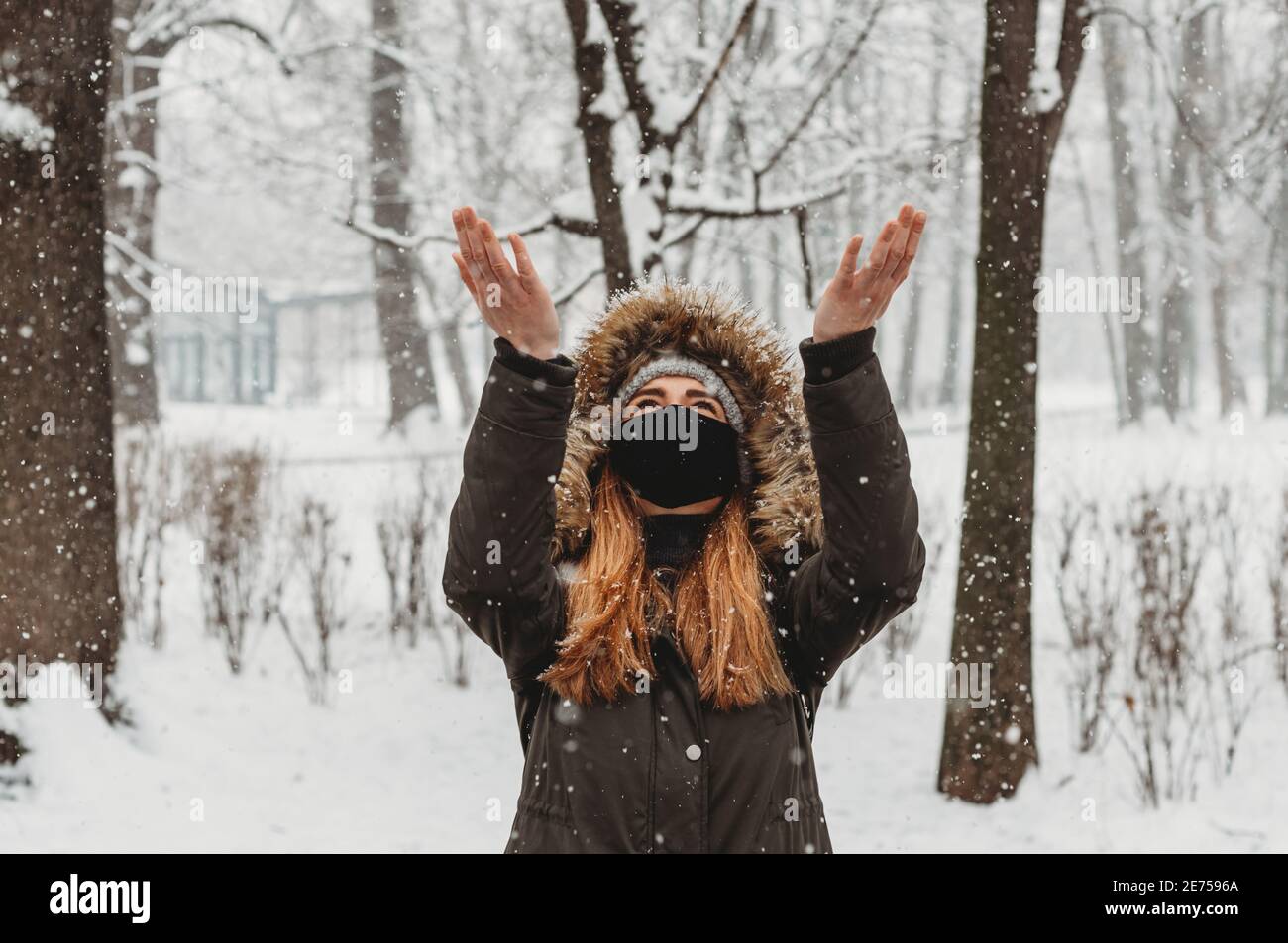femme en hiver avec des vêtements de masque facial appréciant la neige Banque D'Images