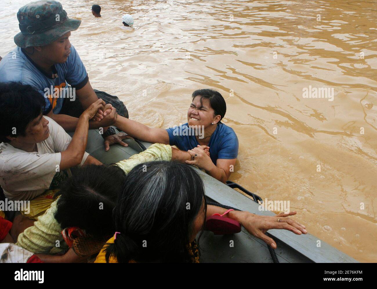 A policeman and other flood victims help a woman get on a rubber boat  during flooding caused by Typhoon Ondoy in Cainta Rizal, east of Manila  September 27, 2009. Nearly 60 people