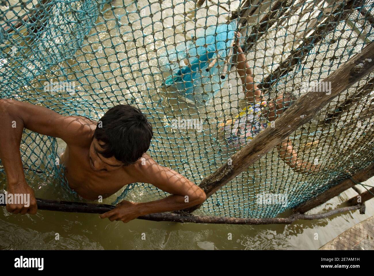 Le pêcheur brésilien Francivaldo de Souza Costa répare un piège à poisson  construit en forme de corral, à marée basse sur des plates-formes de sable  à l'embouchure de l'Amazone à Curuca, le
