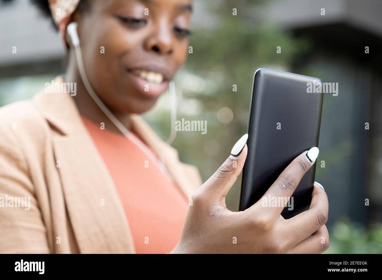 Gros plan de blogueur africain regardant l'écran d'elle téléphone mobile en extérieur Banque D'Images
