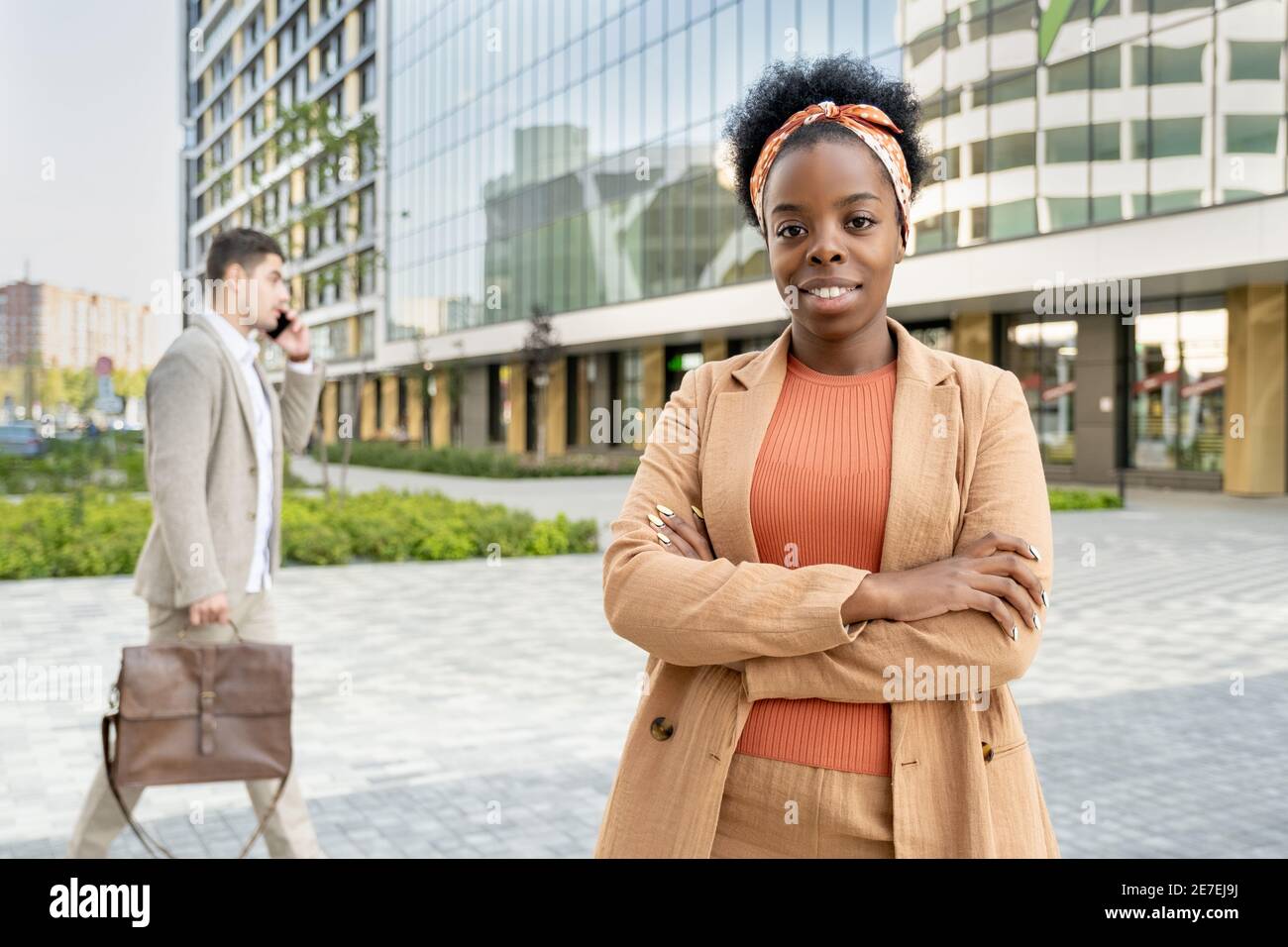 Portrait de la jeune femme africaine souriant à la caméra debout avec ses bras ont traversé la ville Banque D'Images