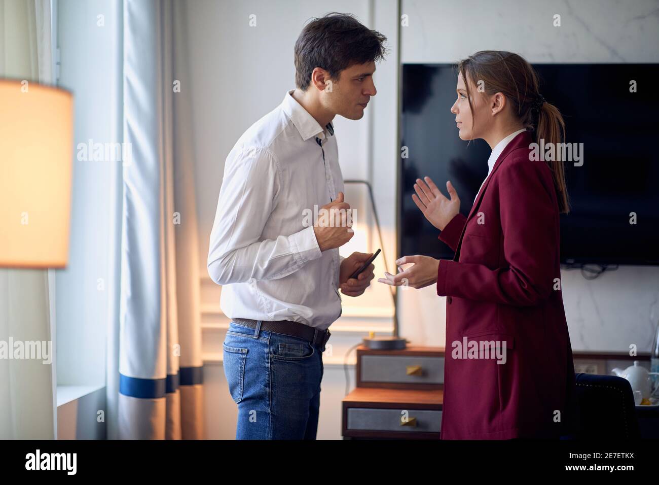 Un jeune couple dans la chambre d'hôtel discutant de problèmes lors de son voyage d'affaires pour une nouvelle affaire. Hôtel, affaires, personnes Banque D'Images