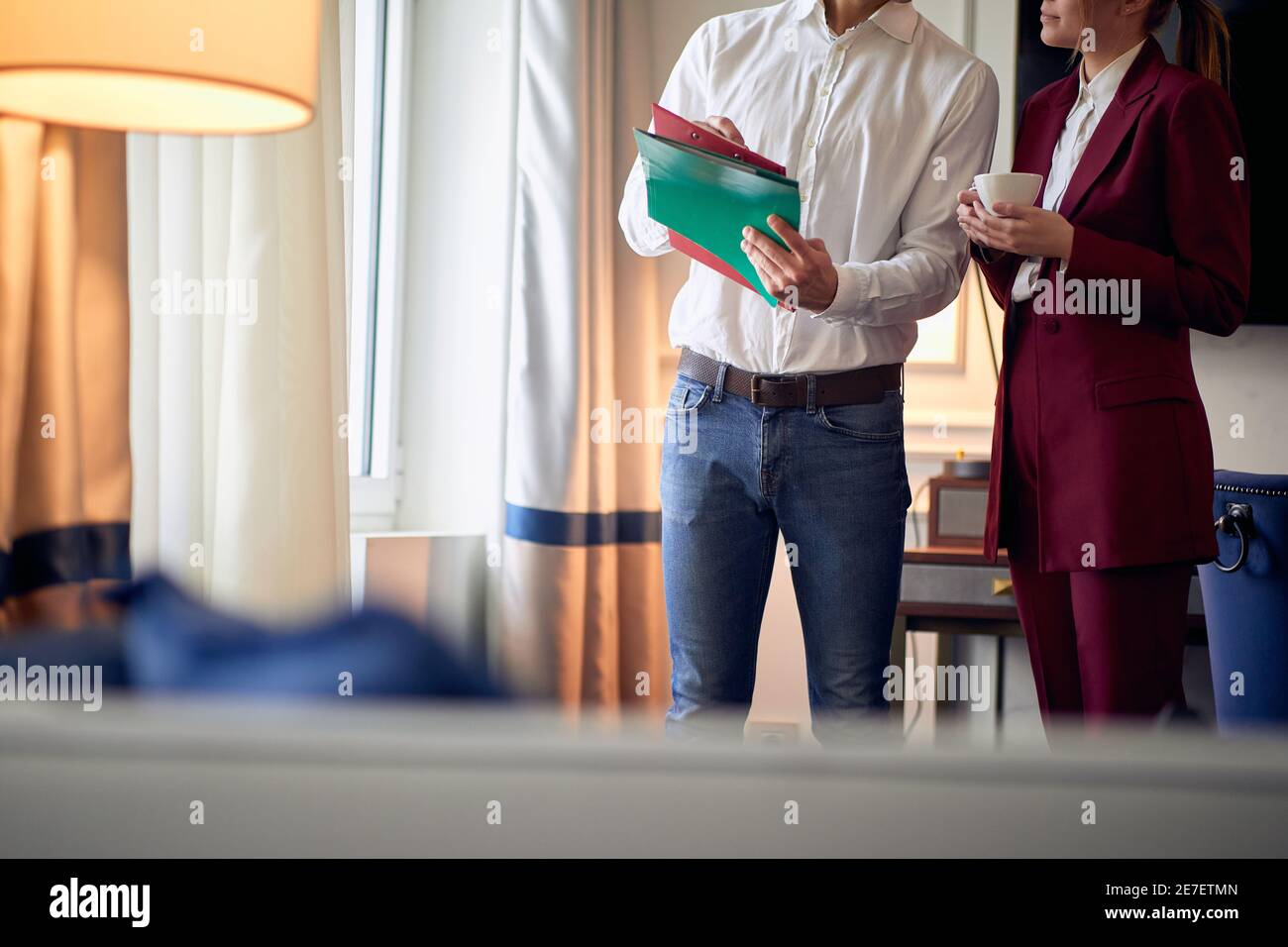 Un jeune couple qui passe une belle matinée dans la chambre d'hôtel en passant par les documents lors de son voyage d'affaires pour une nouvelle affaire. Hôtel, affaires, personnes Banque D'Images