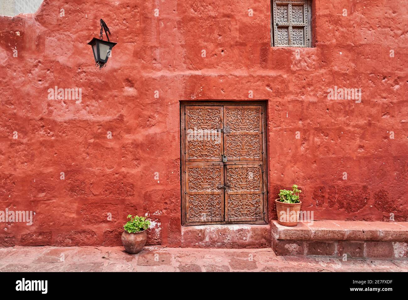 bâtiment colonial espagnol de couleur rouge sur la façade, une lanterne et une ancienne porte en bois avec ornements Banque D'Images