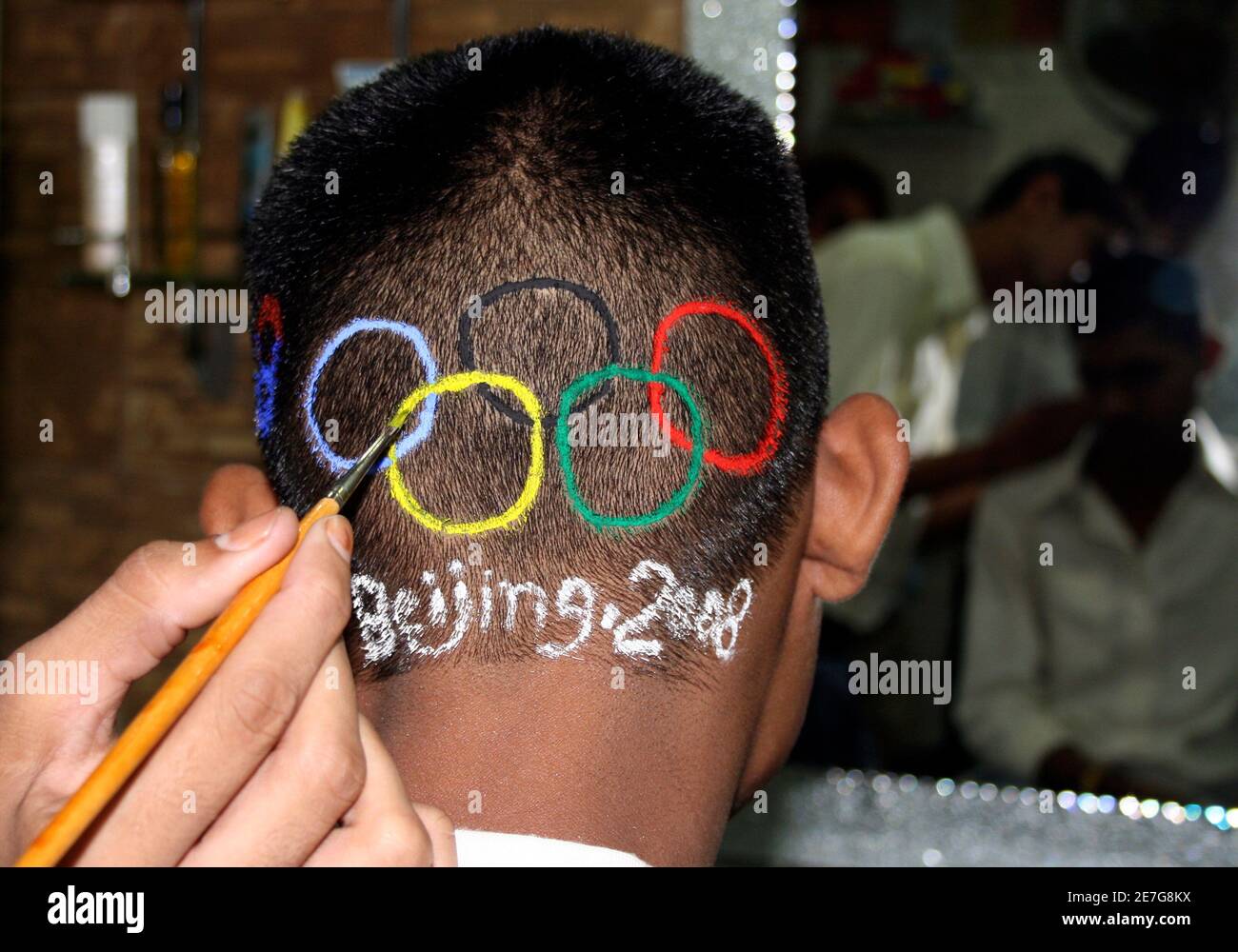 Un homme obtient le logo olympique peint sur sa tête dans la ville indienne occidentale d'Ahmedabad le 8 août 2008. La Chine renaissante a ouvert les Jeux Olympiques vendredi avec une explosion de feux d'artifice lors d'une cérémonie spectaculaire qui a célébré l'histoire de la Chine antique et qui visait à tracer une ligne sous des mois de controverse politique. REUTERS/Amit Dave (INDE) Banque D'Images