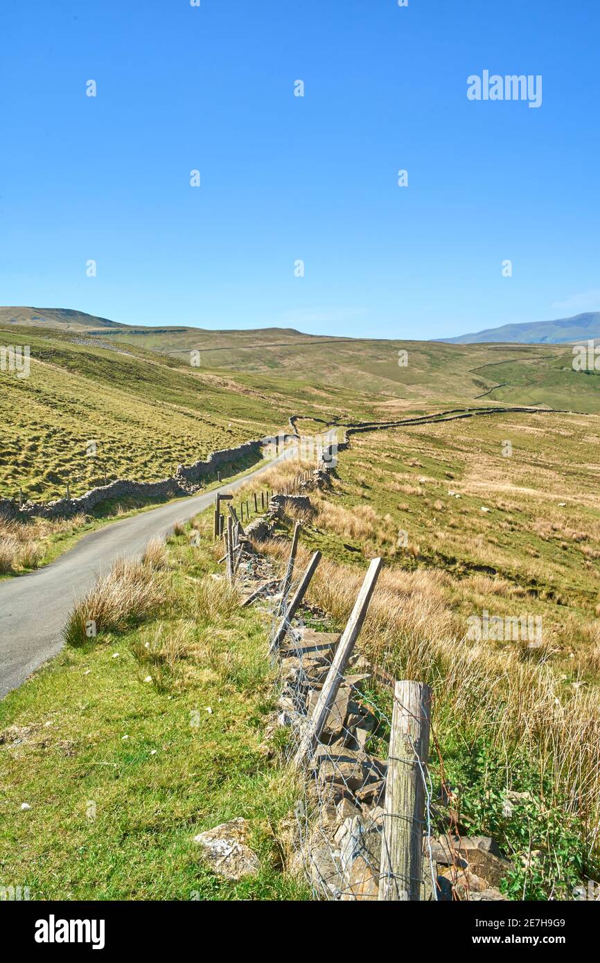 Une route de moorland solitaire haut dans les Pennines et le Yorkshire Dales sous un ciel bleu vif Banque D'Images