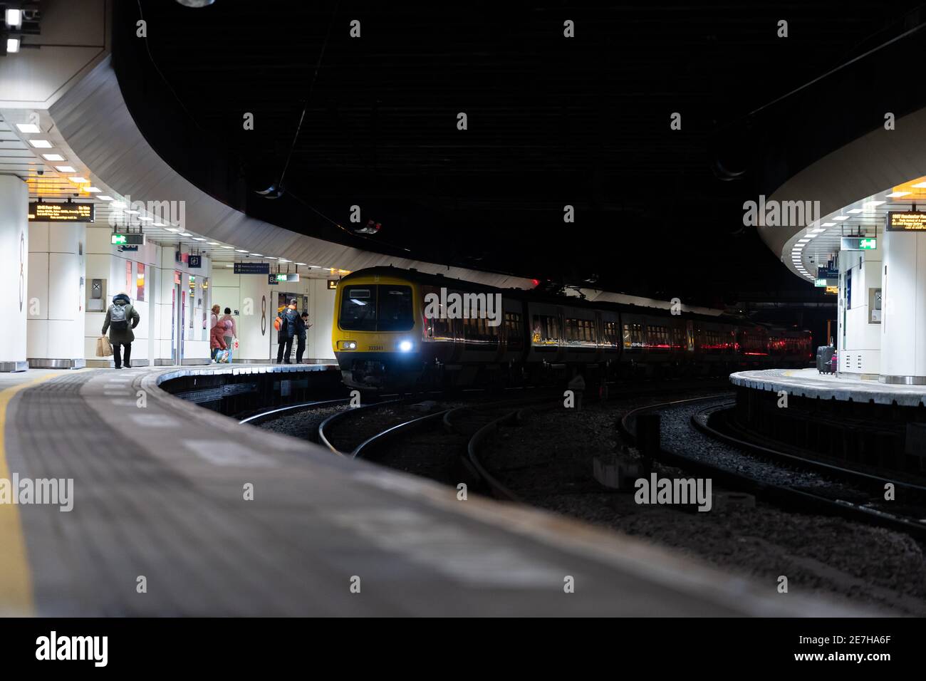 Train de voyageurs avec feux allumés en attente à deux plates-formes souterraines la nuit, en cas de pandémie, les passagers et les acheteurs s'embarquant chariot Banque D'Images