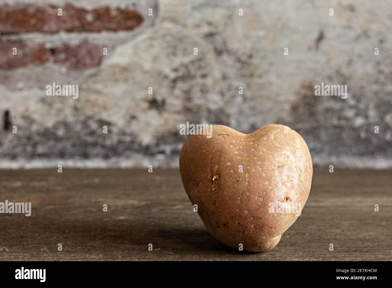 Cœur de la pomme de terre rouge sur fond de millésime. Le concept de l'agriculture, de la récolte, du végétarisme. Saint-Valentin. Carré, nourriture moche Banque D'Images