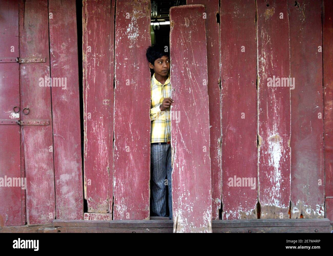 Un garçon regarde d'un magasin fermé lors d'une manifestation contre la violence à Nandigram, dans la ville indienne de Siliguri, dans le nord-est du pays, le 16 mars 2007. Une grève a appelé à protester contre le meurtre de 14 villageois manifestant contre un centre industriel prévu qui a fermé vendredi des écoles, des bureaux et des magasins dans l'État indien du Bengale occidental contrôlé par les communistes. REUTERS/Rupak de Chowdhuri (INDE) Banque D'Images