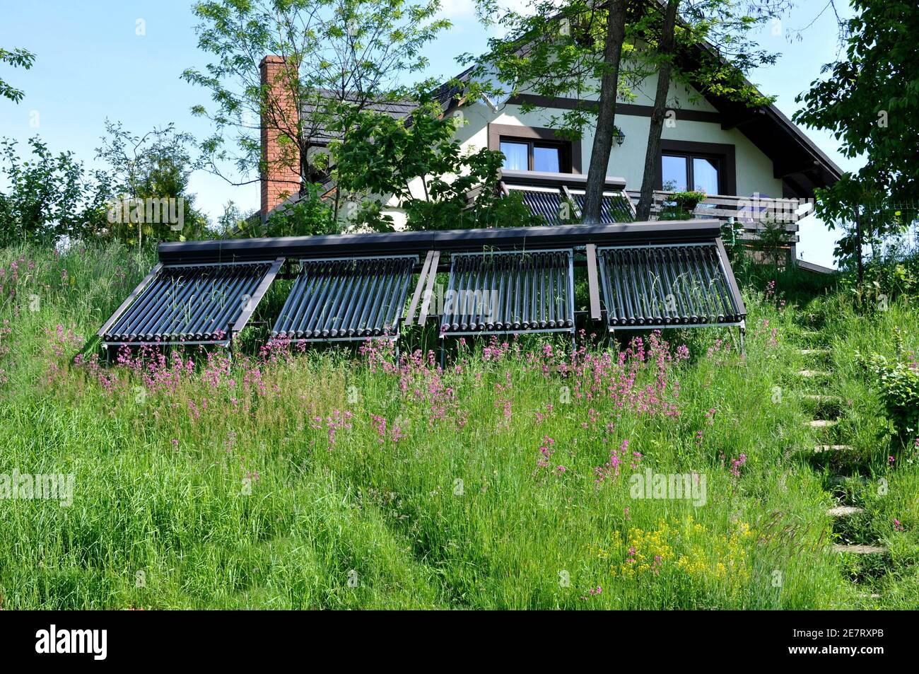 panneaux d'énergie solaire en face d'une maison dans le jardin. Banque D'Images