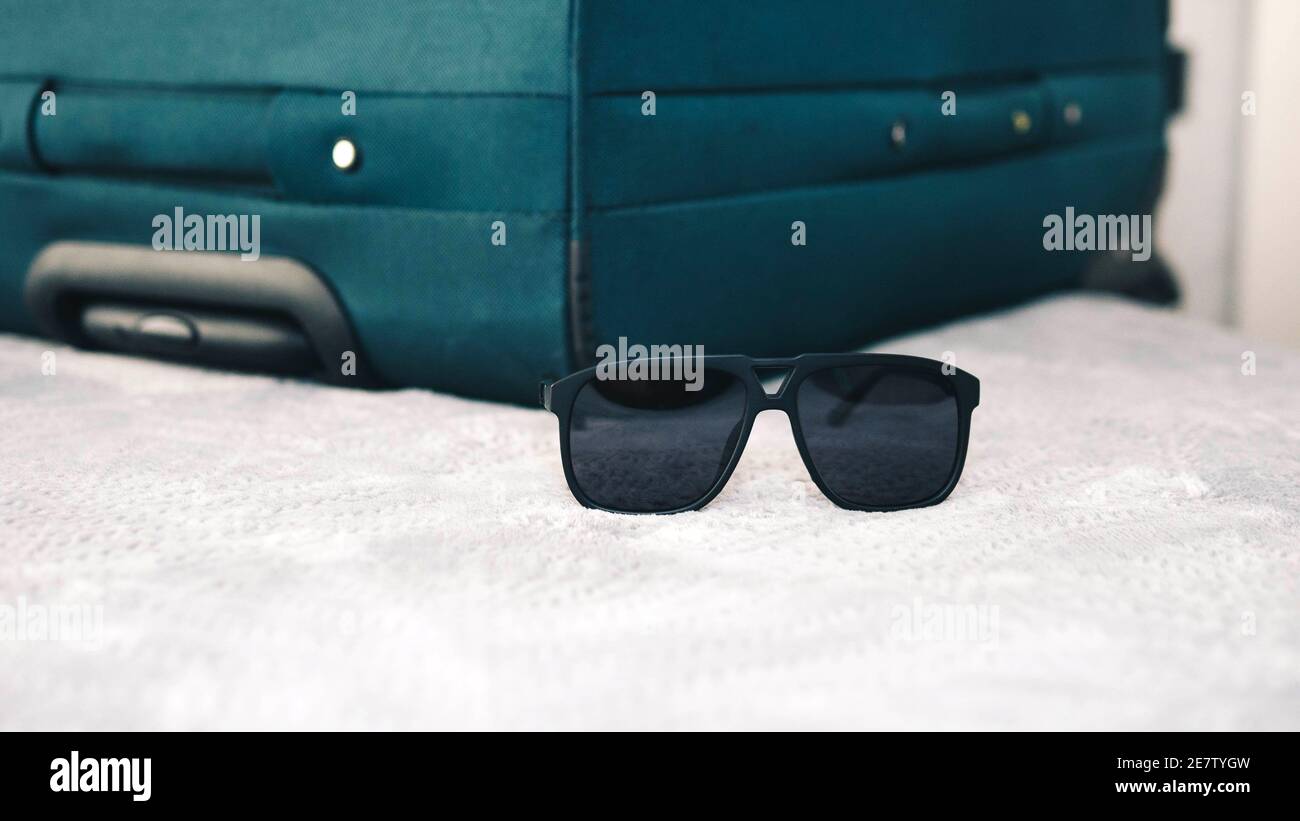 Articles de voyage, lunettes de soleil avec une valise sur le lit, concept  de voyage, lunettes de soleil noires du soleil Photo Stock - Alamy