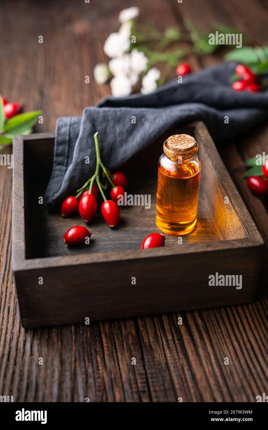 Huile de graines de rosehip pure dans une bouteille en verre, remède pour la peau et les cheveux sur fond rustique en bois Banque D'Images