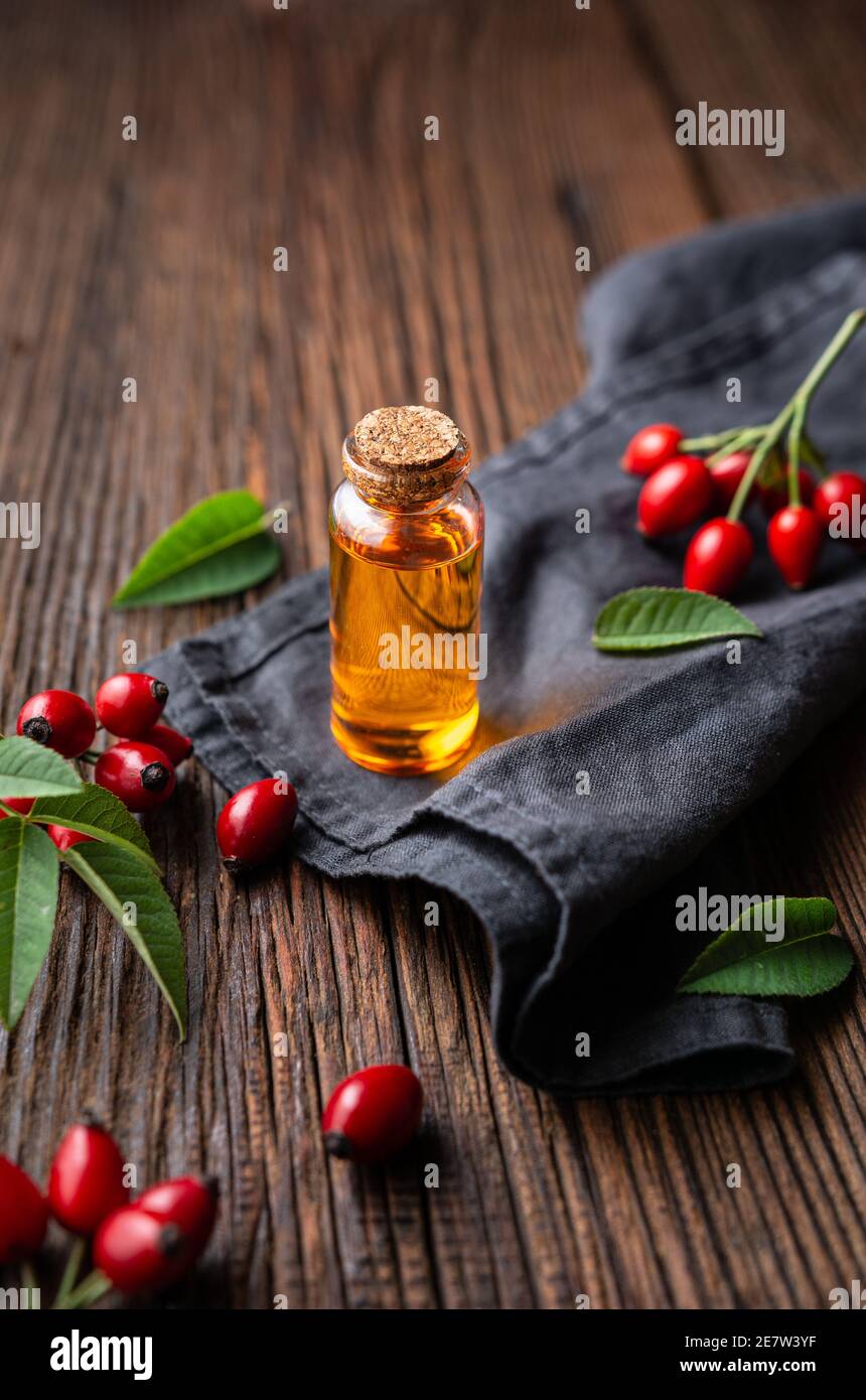 Huile de graines de rosehip pure dans une bouteille en verre, remède pour la peau et les cheveux sur fond rustique en bois Banque D'Images