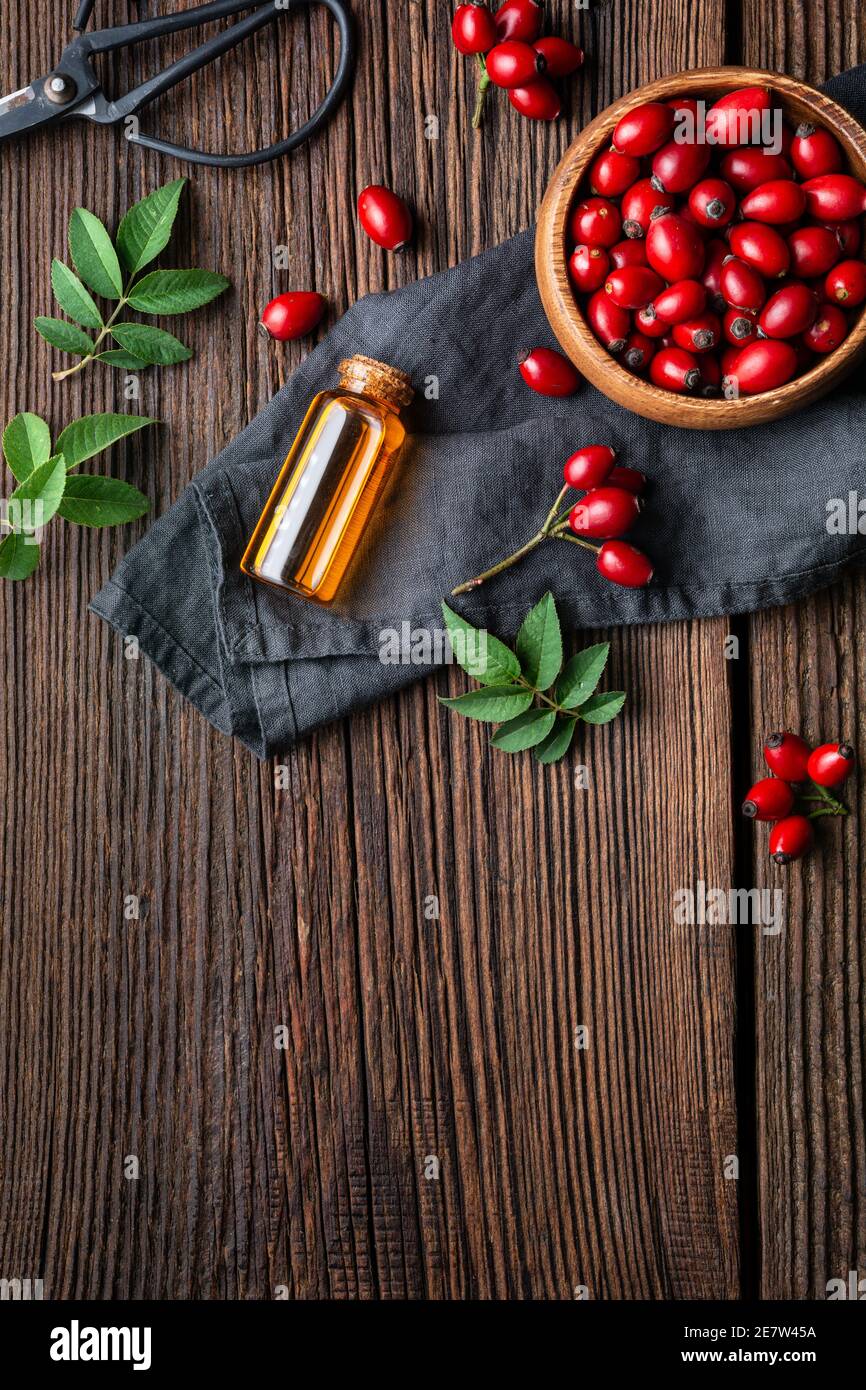 Huile de graines de rosehip pure dans une bouteille en verre, remède pour la peau et les cheveux sur fond rustique en bois avec espace de copie Banque D'Images