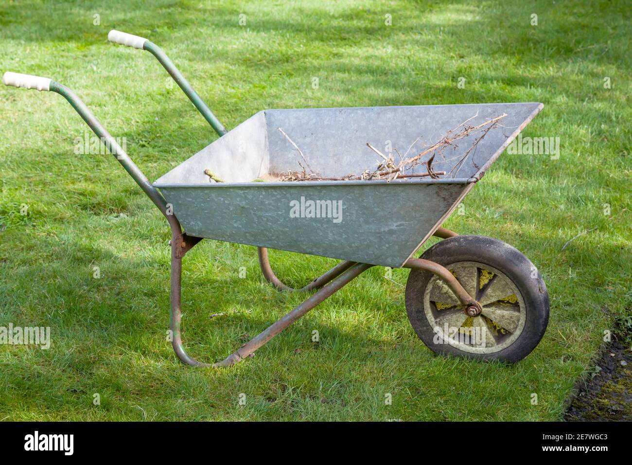 Brouette à proximité sur une pelouse dans un jardin en Angleterre, au Royaume-Uni. Entretien du jardin. Banque D'Images
