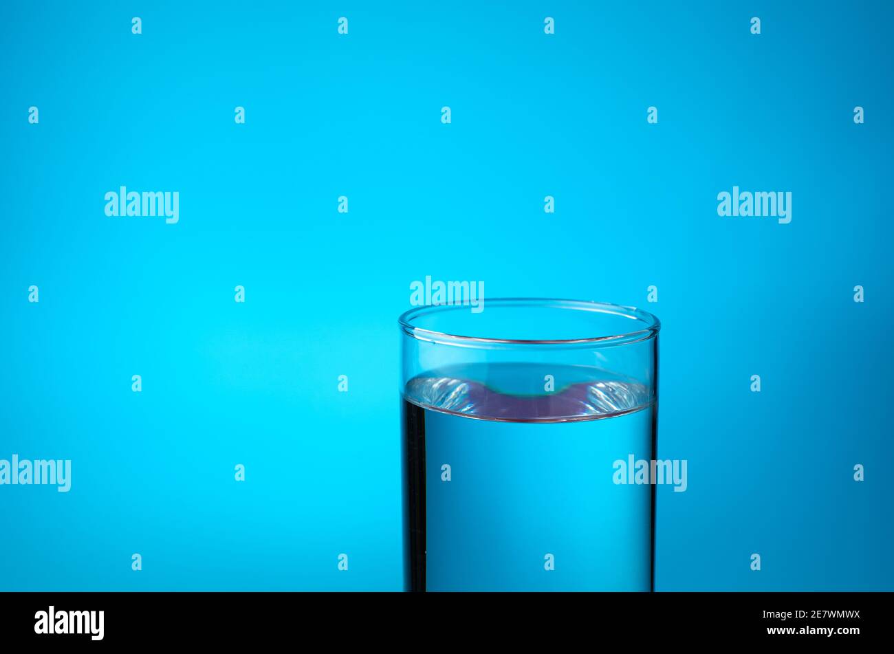 Verre transparent rempli d'eau sur fond bleu. Vue latérale avec espace de copie. Banque D'Images