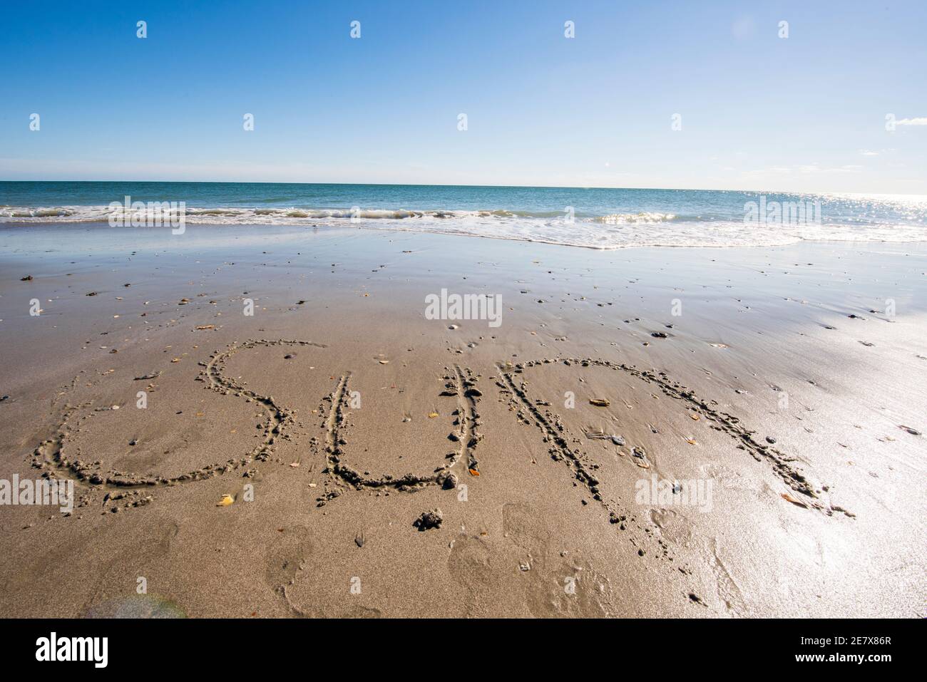 Le mot SOLEIL écrit dans le sable au bord de la mer. Banque D'Images