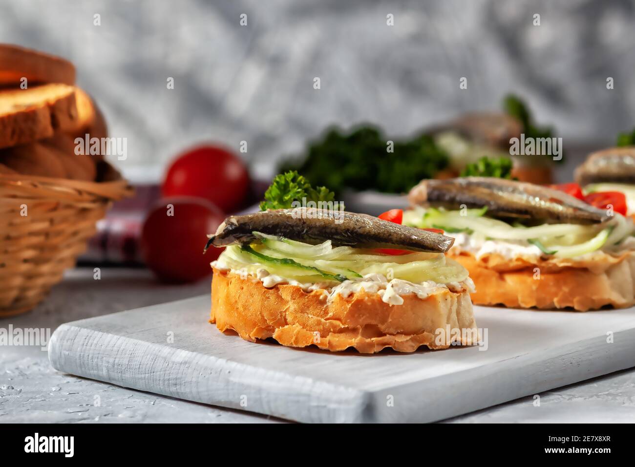 Sandwich au sprat fumé - poisson, concombre frais et tomate. Croque-monsieur sur des tranches de pain grillées Banque D'Images