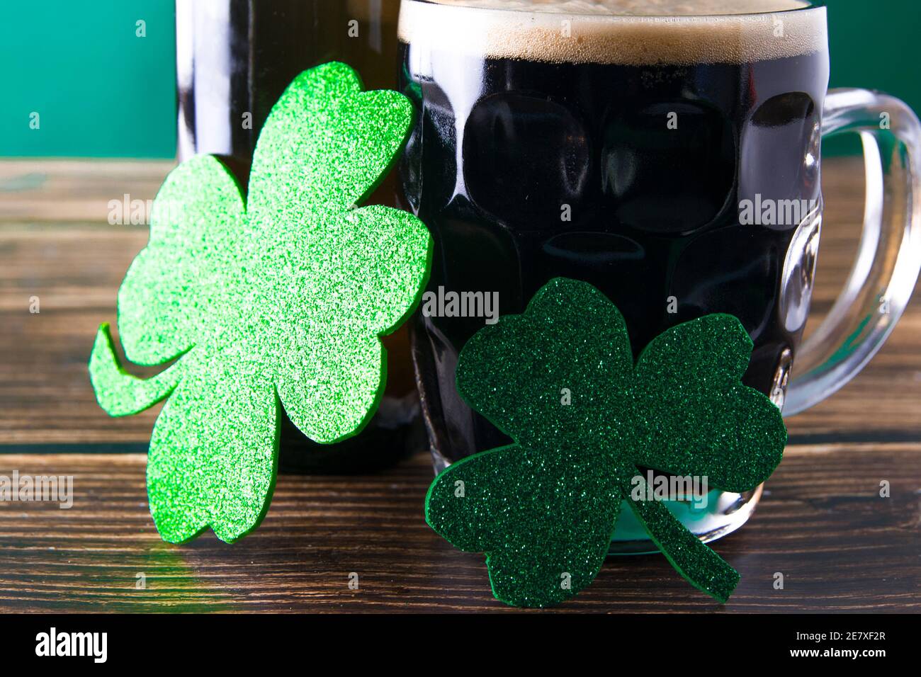 Gros plan de deux feuilles de trèfle brillantes sur une tasse de stout. St. Patrick et Stout concept Banque D'Images
