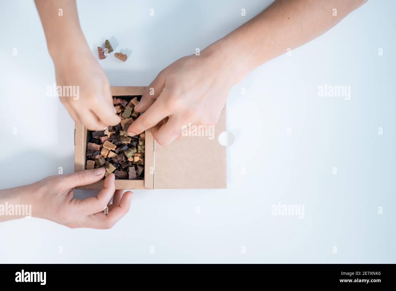 vue de dessus des mains prenez des bonbons faits maison ou des bonbons au chocolat de la boîte à papier Banque D'Images