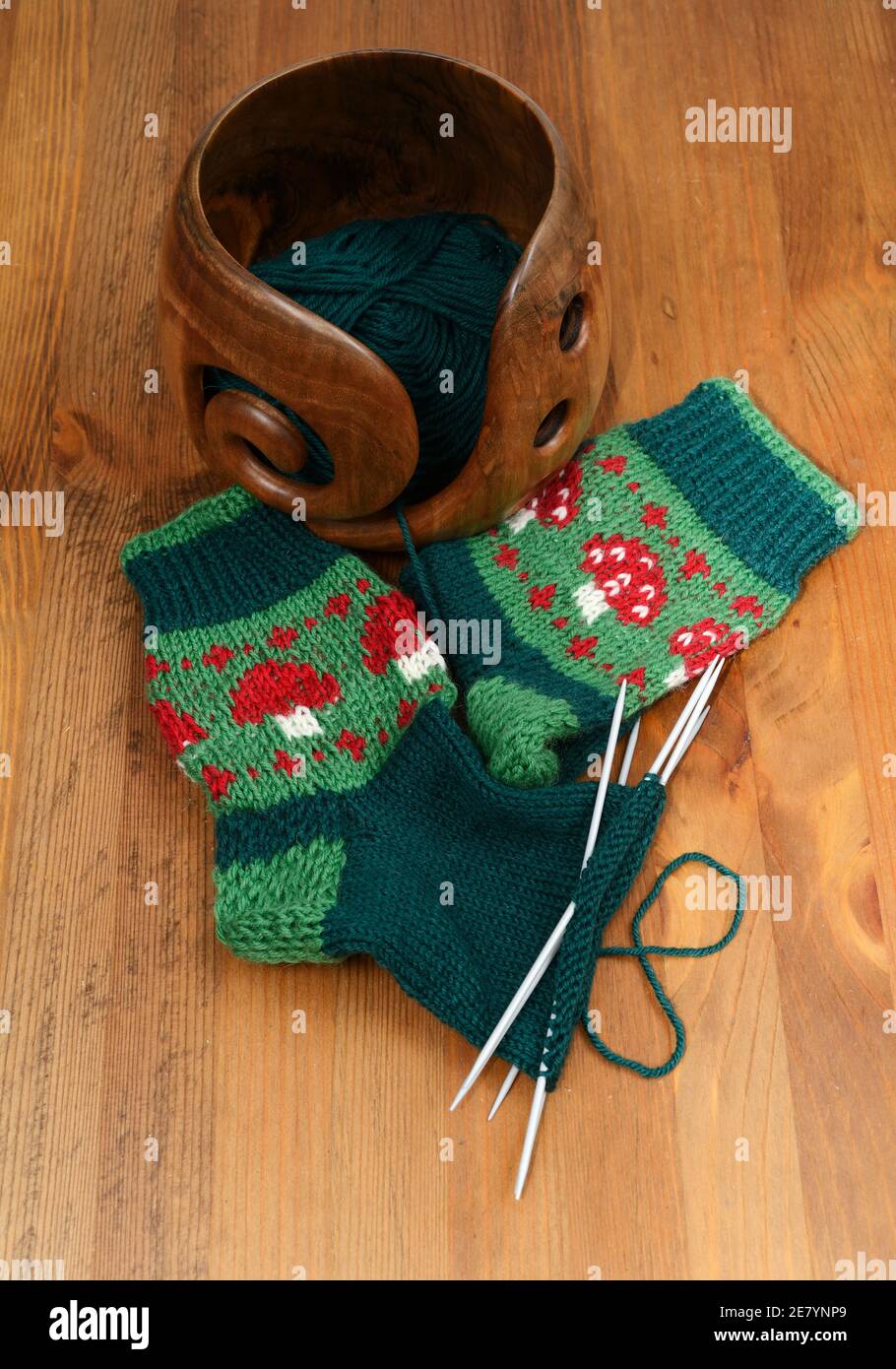 une paire de chaussettes en laine avec amanita et laine dans un bois bol fait main Banque D'Images