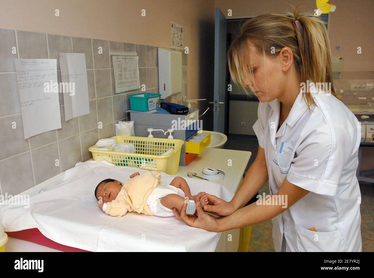 Une infirmière place un bracelet électronique à la cheville d'un nouveau-né  à l'hôpital intercommunal du Raincy-Montfermeil, au nord de Paris, le 12  avril 2007. Cet hôpital de maternité des banlieues parisiennes qui