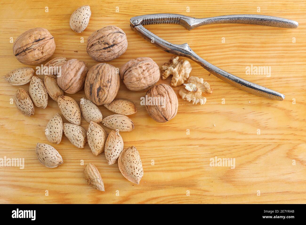 Noix de Grenoble savoureuses, amande et casse-noisette en métal sur fond de bois. Banque D'Images