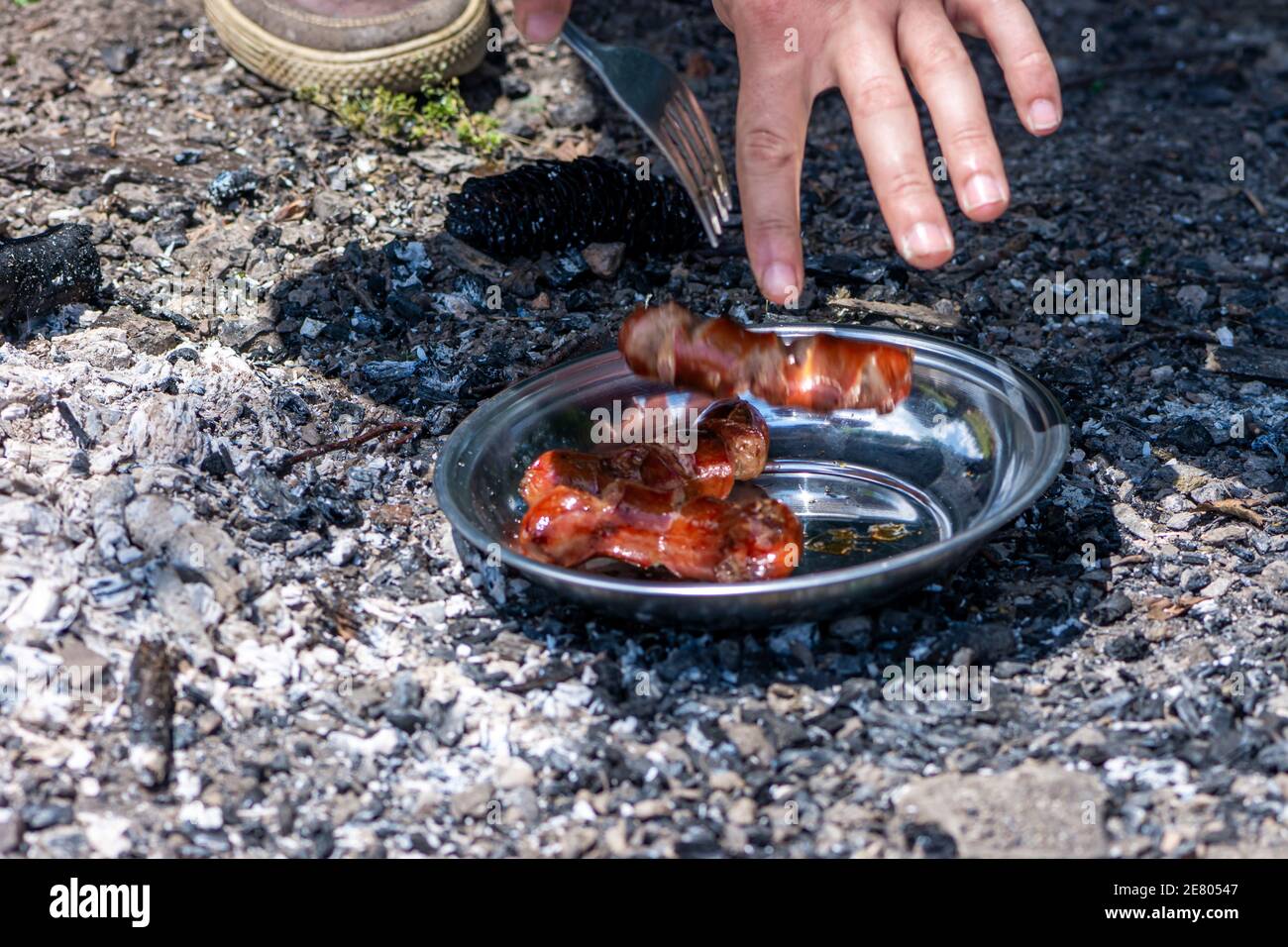 Main de l'homme mettant des saucisses grillées sur l'assiette en mouvement flou Banque D'Images