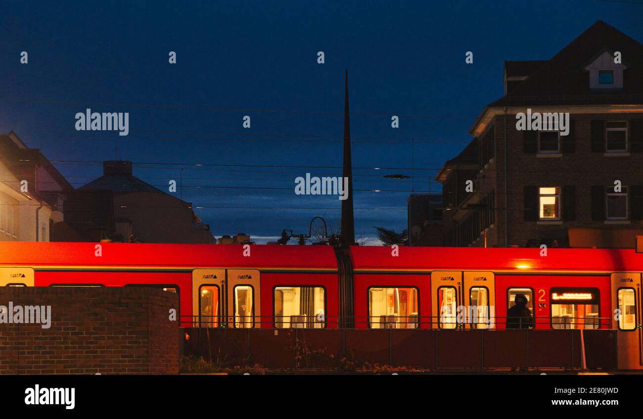 Un train rouge arrive à Rüsselsheim en Allemagne dans la soirée et la scène avec l'ancien bâtiment et le train moderne On dirait à New York Banque D'Images