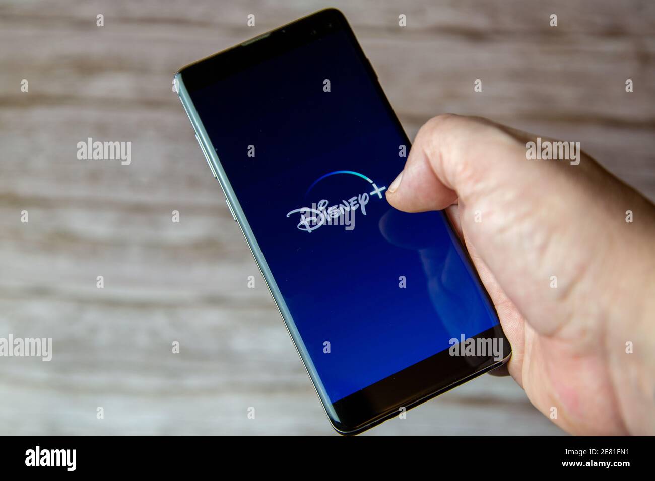 Une main tenant un téléphone portable ou un téléphone cellulaire avec l'application disney plus s'ouvre à l'écran Banque D'Images