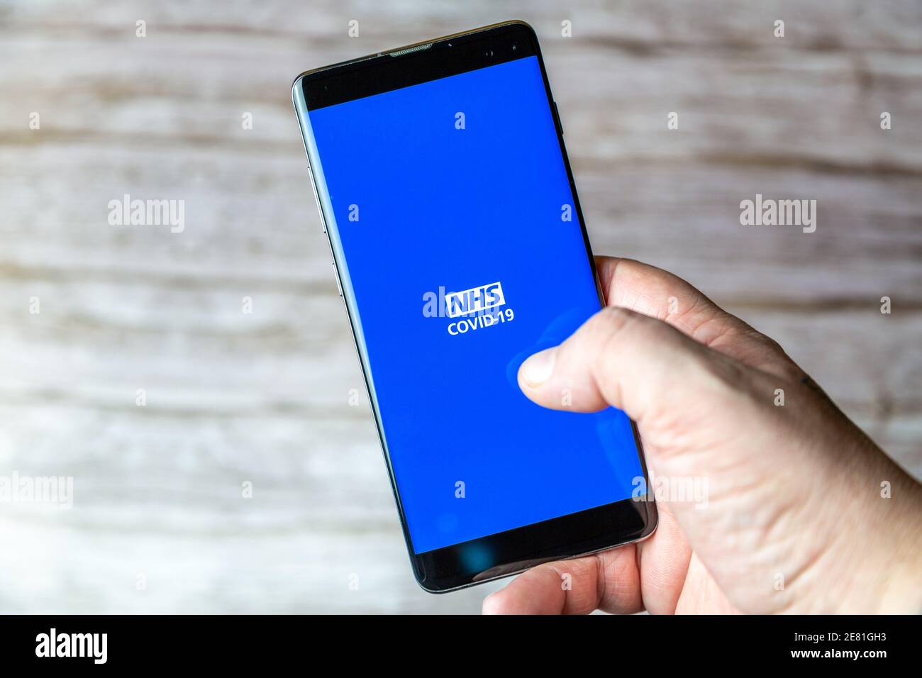 Une main tenant un téléphone portable ou un téléphone cellulaire avec L'application NHS Covid-19 TRACK and trace s'ouvre à l'écran Banque D'Images