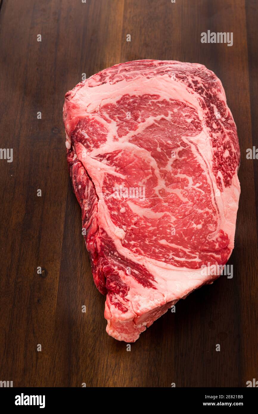 Un steak Ribeye brut de New York strip sur une planche à découper. Banque D'Images
