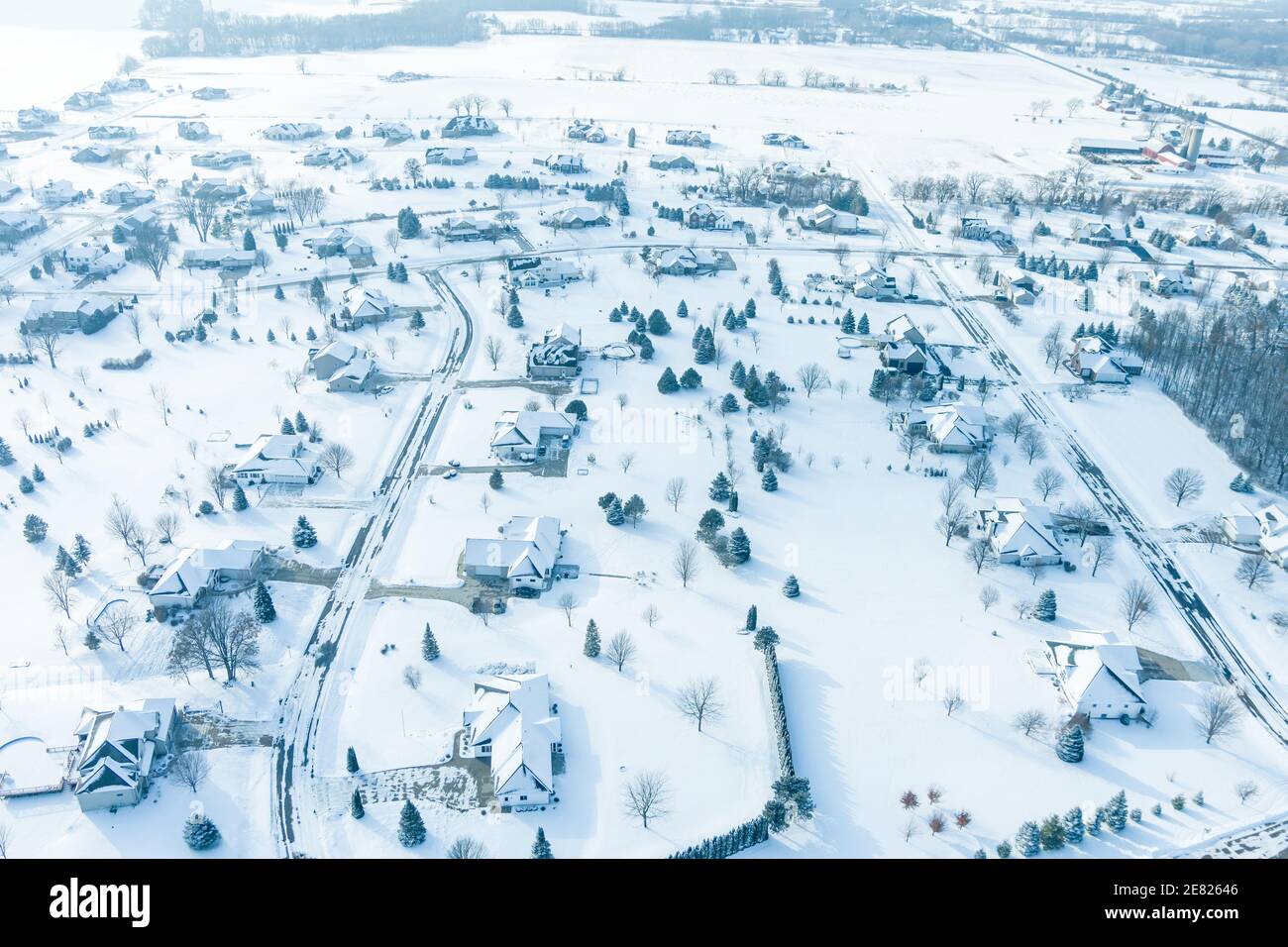 Survolant de grandes maisons avec de grands chantiers dans un quartier de banlieue juste après une neige fraîche. Banque D'Images