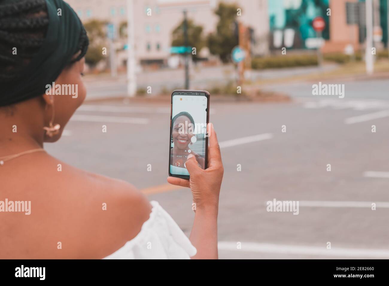 Femme africaine souriante prenant un selfie avec un smartphone Banque D'Images