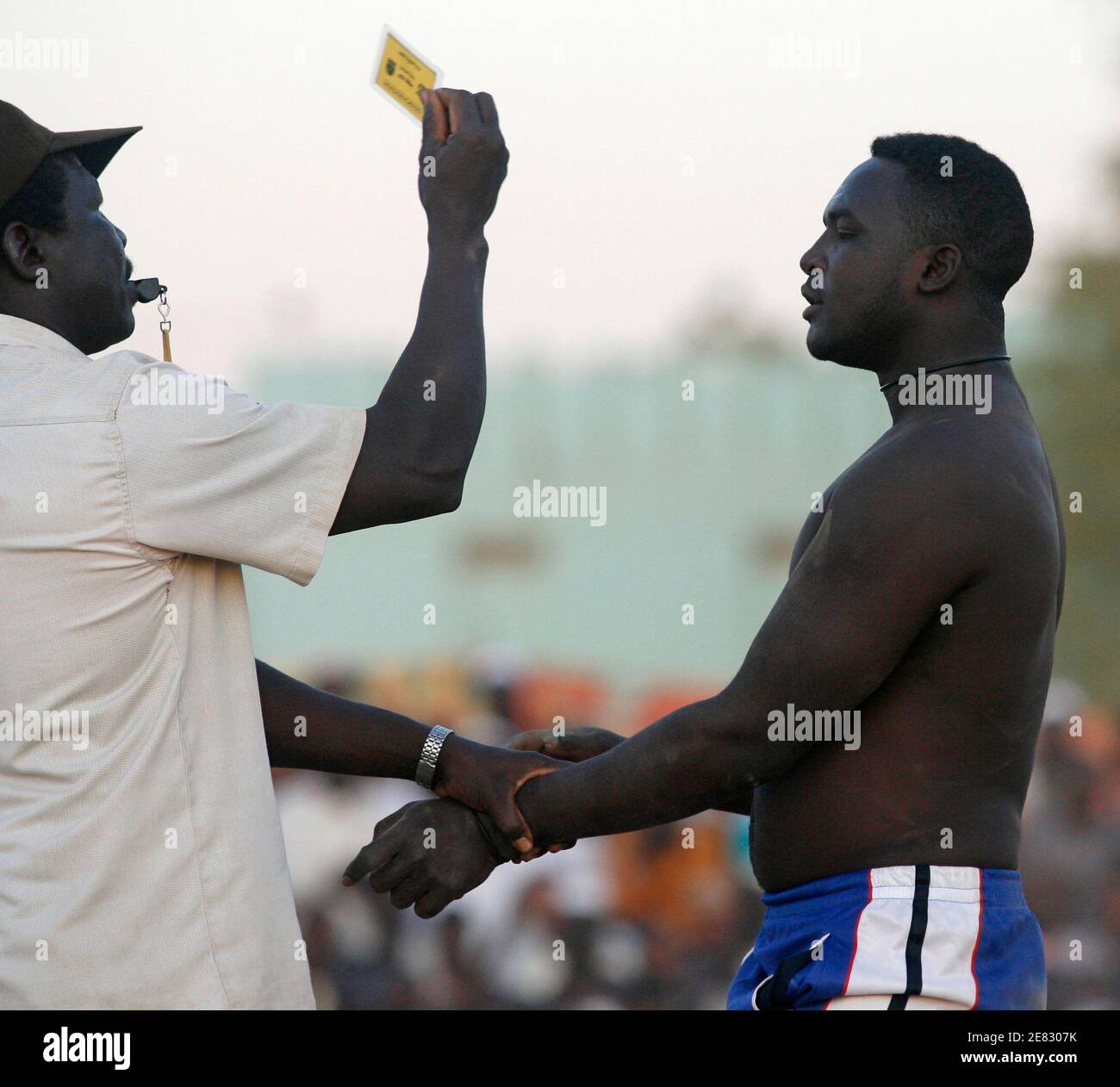 A Nuba wrestler receives a yellow card from the referee for hitting his  opponent during a Nuba wrestling competition in the northern Khartoum  district of Haj Yusef December 8, 2006. The traditional
