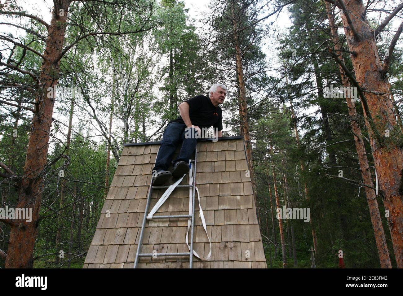 Treehotel co-founder Kent Lindvall sits on the roof of The Cabin on the construction site of Treehotel in the Swedish village of Harads, July 5, 2010. A lofty new hotel concept is set to open in a remote village in northern Sweden, which aims to elevate the simple treehouse into a world-class destination for design-conscious travellers. Treehotel, located in Harads about 60 km south of the Arctic Circle, will consist of four rooms when it opens on July 17th: The Cabin, The Blue Cone, The Nest and The Mirrorcube. Picture taken July 5, 2010. To match Reuters Life! SWEDEN-TREEHOTEL/ REUTER Banque D'Images