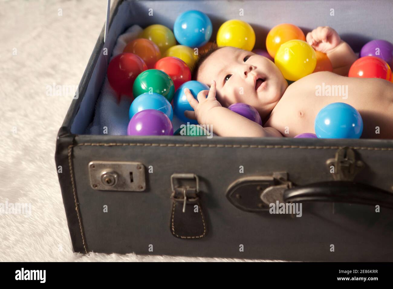 Un bébé allongé dans la valise avec des boules de couleur photo de haute qualité Banque D'Images