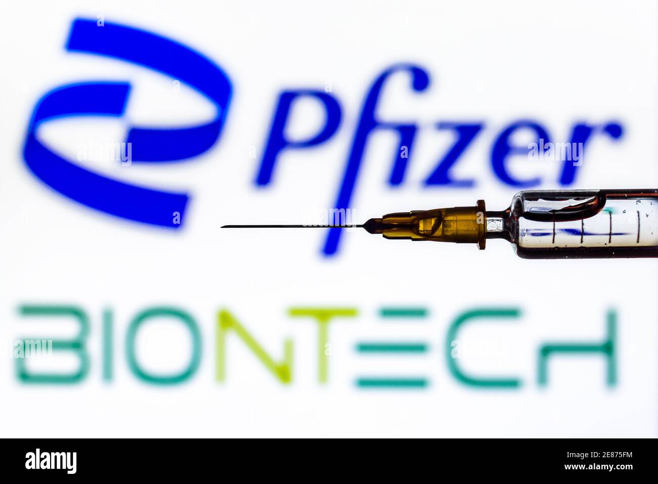 Vienne Autriche janvier.30 2021, seringue avec liquide rétroéclairé par les logos de Pfizer et Biontech, développeurs du vaccin Covid19 Banque D'Images