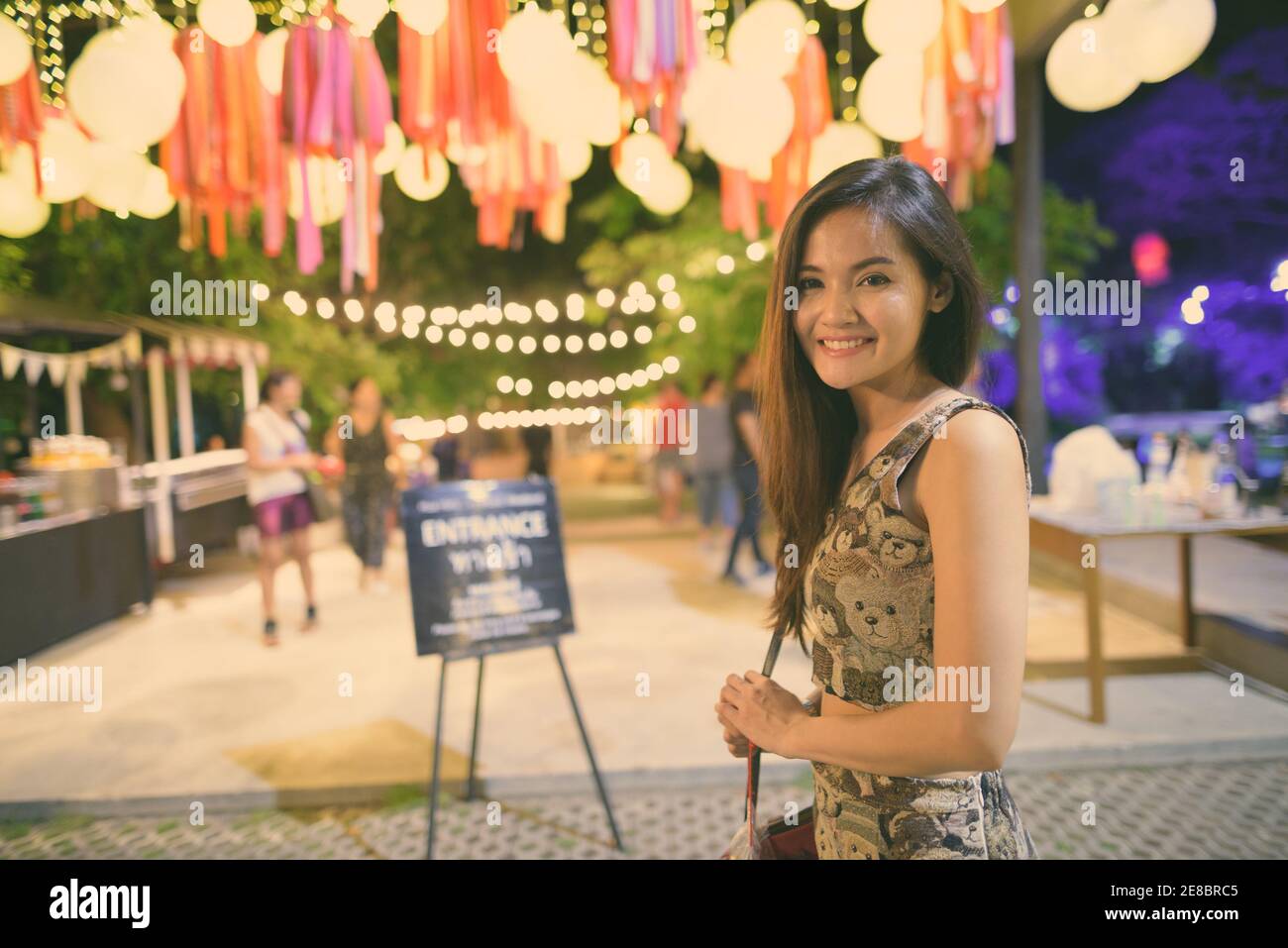 Young happy Asian woman smiling à l'entrée de l'open live band dans le marché de nuit de Hua Hin, Thaïlande Banque D'Images