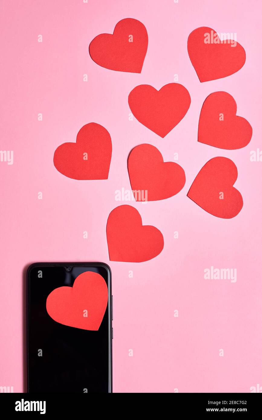 Les cœurs de papier sortent d'un smartphone, la Saint-Valentin, l'amour et le concept de technologie. Banque D'Images