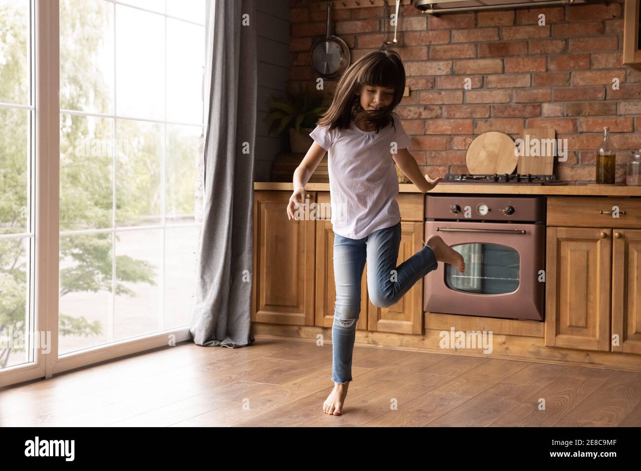 Bonne mignonne petite fille dansant dans la cuisine, s'amuser Banque D'Images