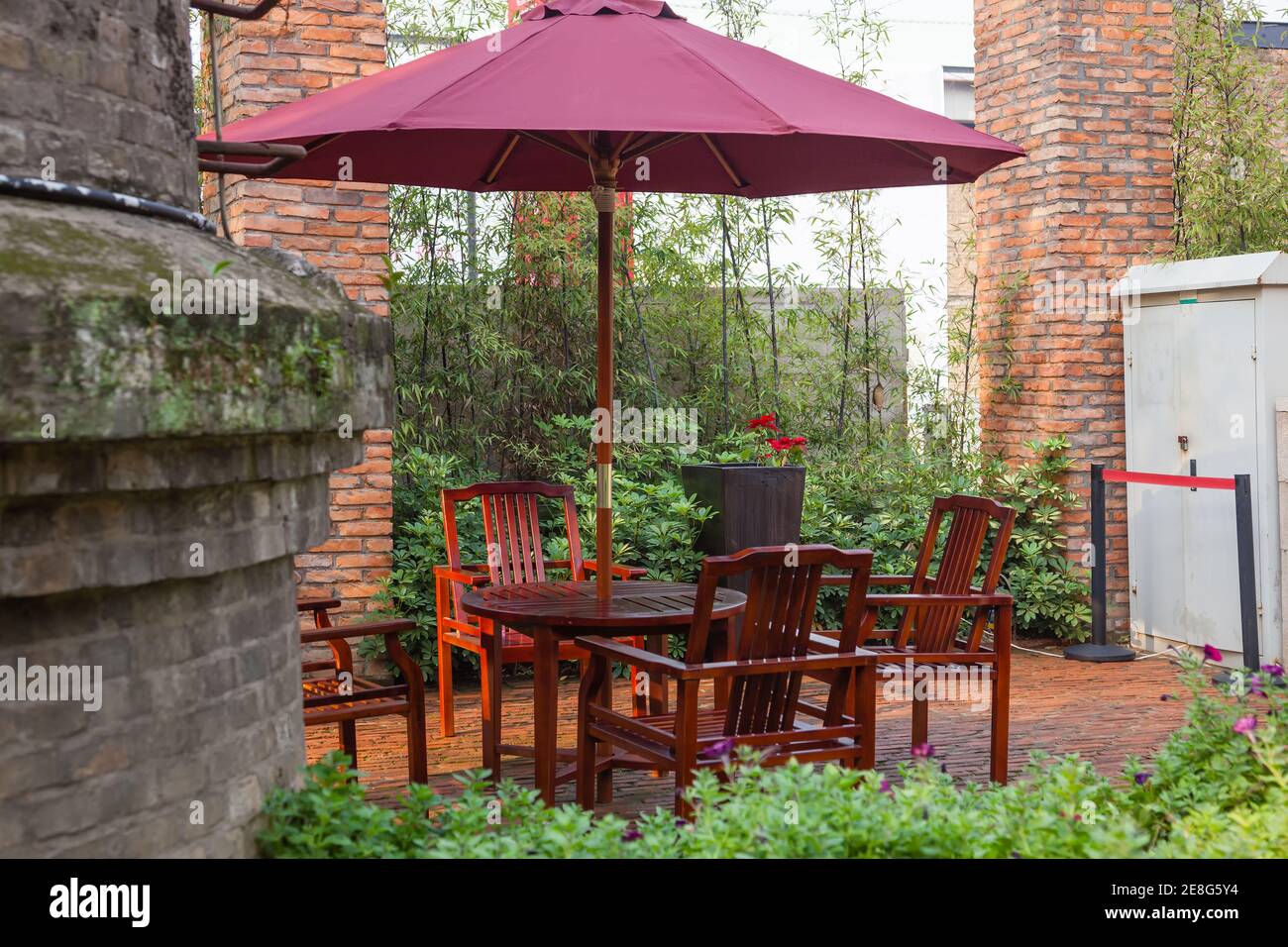Patio d'été avec tables et chaises en bois sous parapluie dans jardin Banque D'Images